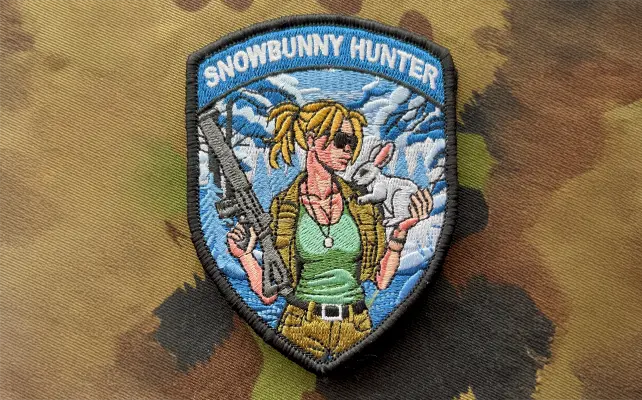 Zugbadge ricamato "SNOWBUNNY HUNTER" con pin-up soldatessa, fucile e coniglio davanti a montagne innevate, patch militare in stile svizzero.